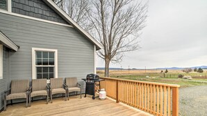A covered deck with a grill, two wicker chairs, and a view of the countryside. - Secluded Bonanza Home w/ Antique Furnishings (Bonanza)