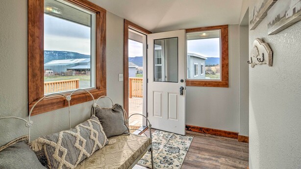 A hallway with a bench, a door, and a view of a building and mountains. - Secluded Bonanza Home w/ Antique Furnishings (Bonanza)