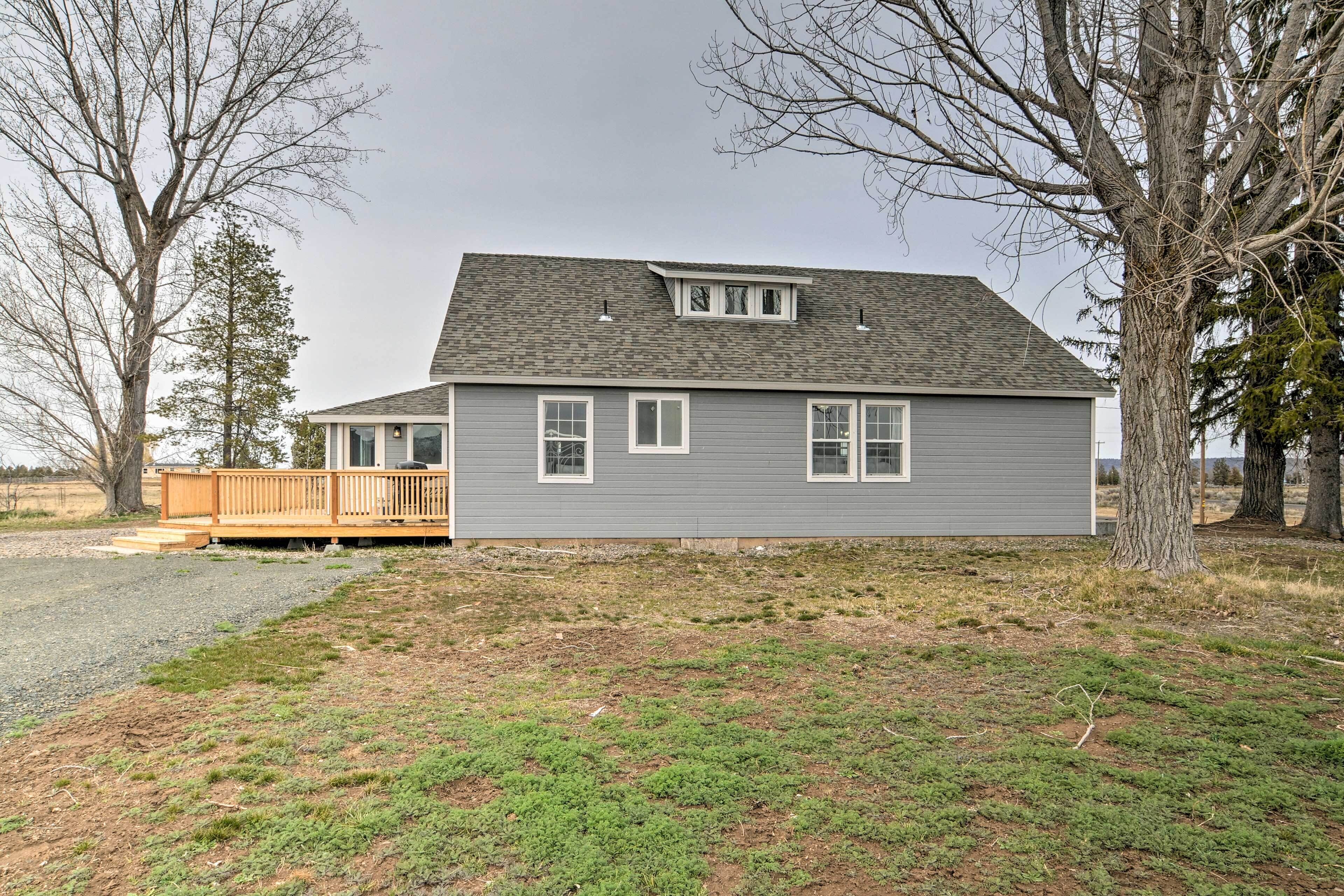 A single-story house with a grey exterior and a wooden deck.