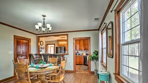A dining area with wooden chairs and a round table, a kitchen with wooden cabinets, and a large window with a view. - Secluded Bonanza Home w/ Antique Furnishings (Bonanza)