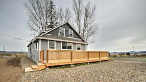 A single-story house with a wooden deck, a gravel driveway, and a mountainous backdrop. - Secluded Bonanza Home w/ Antique Furnishings (Bonanza)