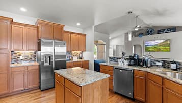 A modern kitchen with wooden cabinets, stainless steel appliances, granite countertops, and a built-in dishwasher.