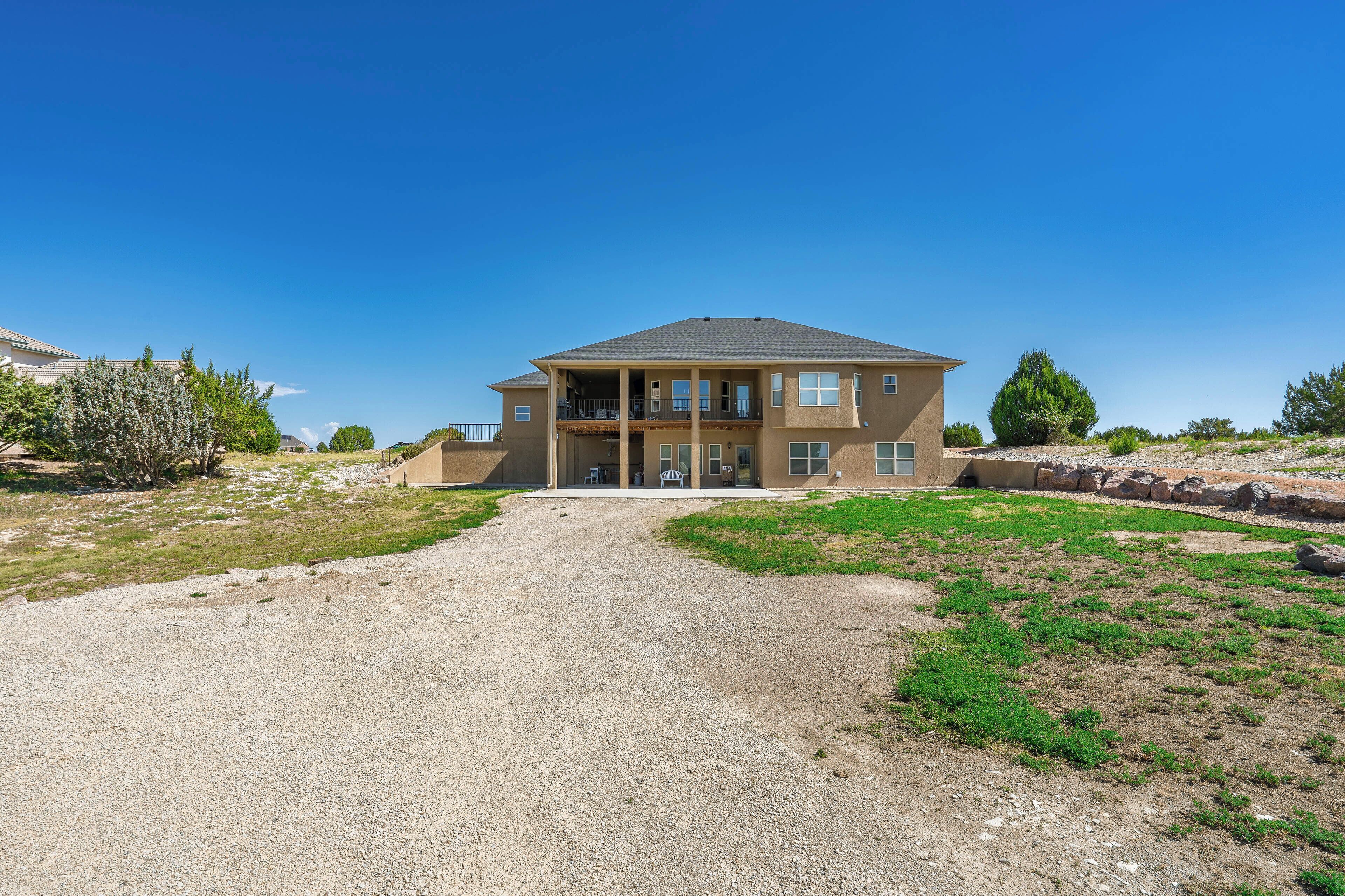 A two-story house with a gravel driveway leading to a front porch.
