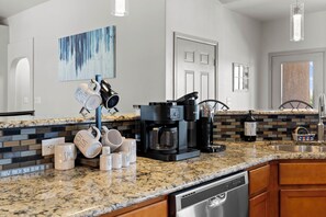 A modern kitchen with granite countertops, a coffee maker, and various mugs. - Mountain-view Deck! Pueblo Family Home (Pueblo)