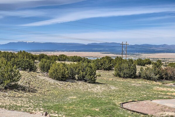 A landscape with a power line structure, sparse vegetation, and distant mountains.