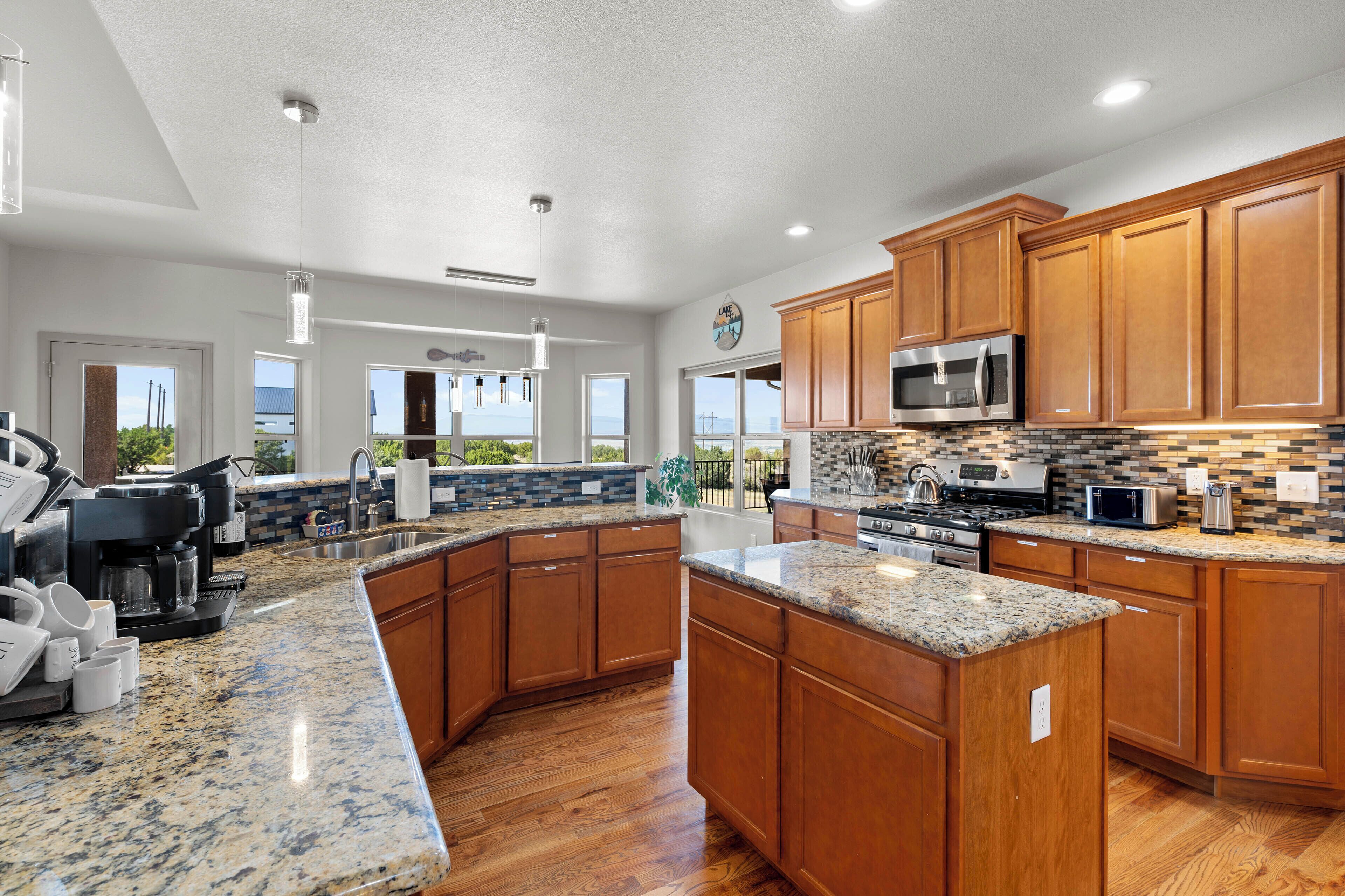 A spacious kitchen with granite countertops, wooden cabinets, and a large island.