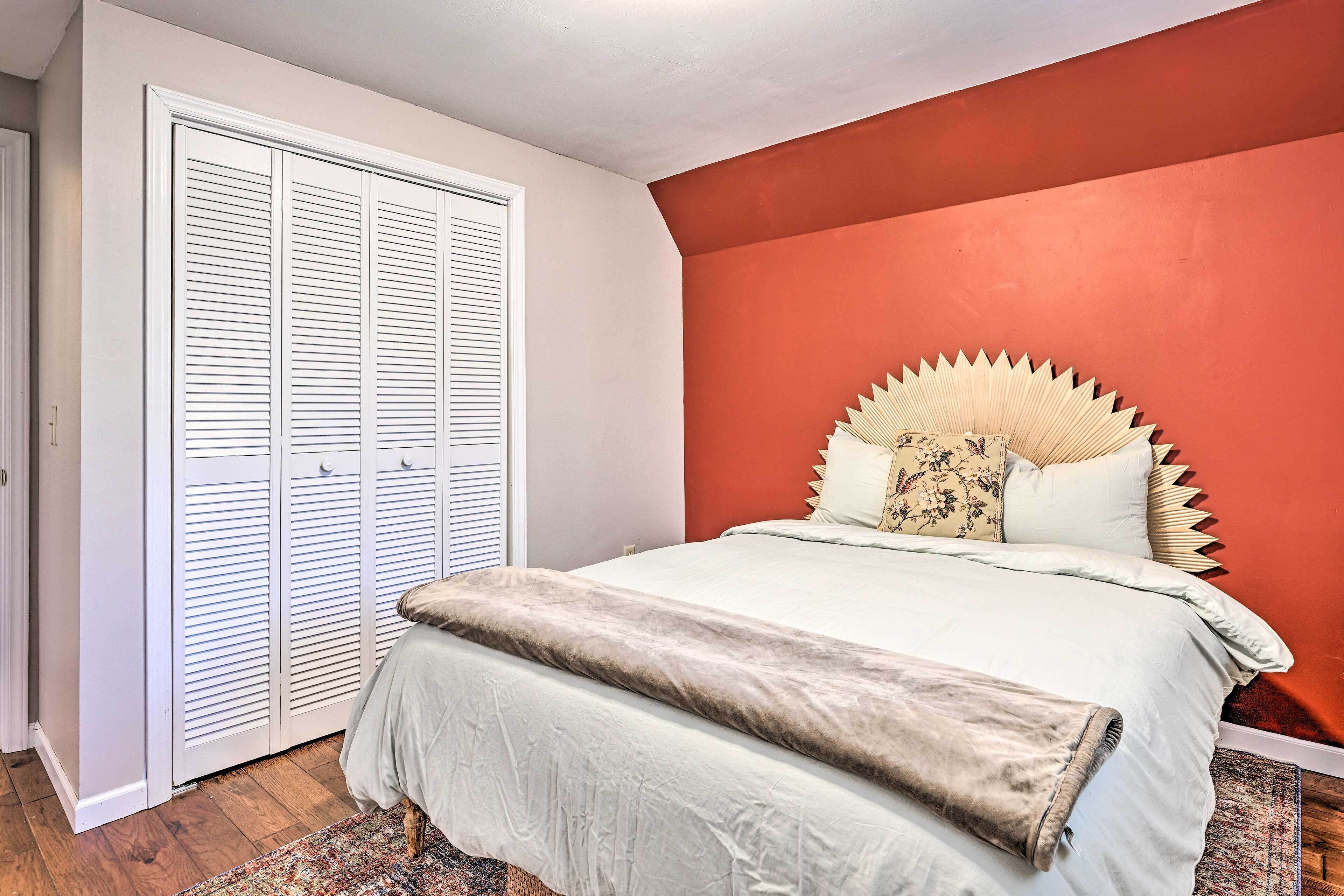 A bedroom with a bed, a large closet, and a red accent wall.