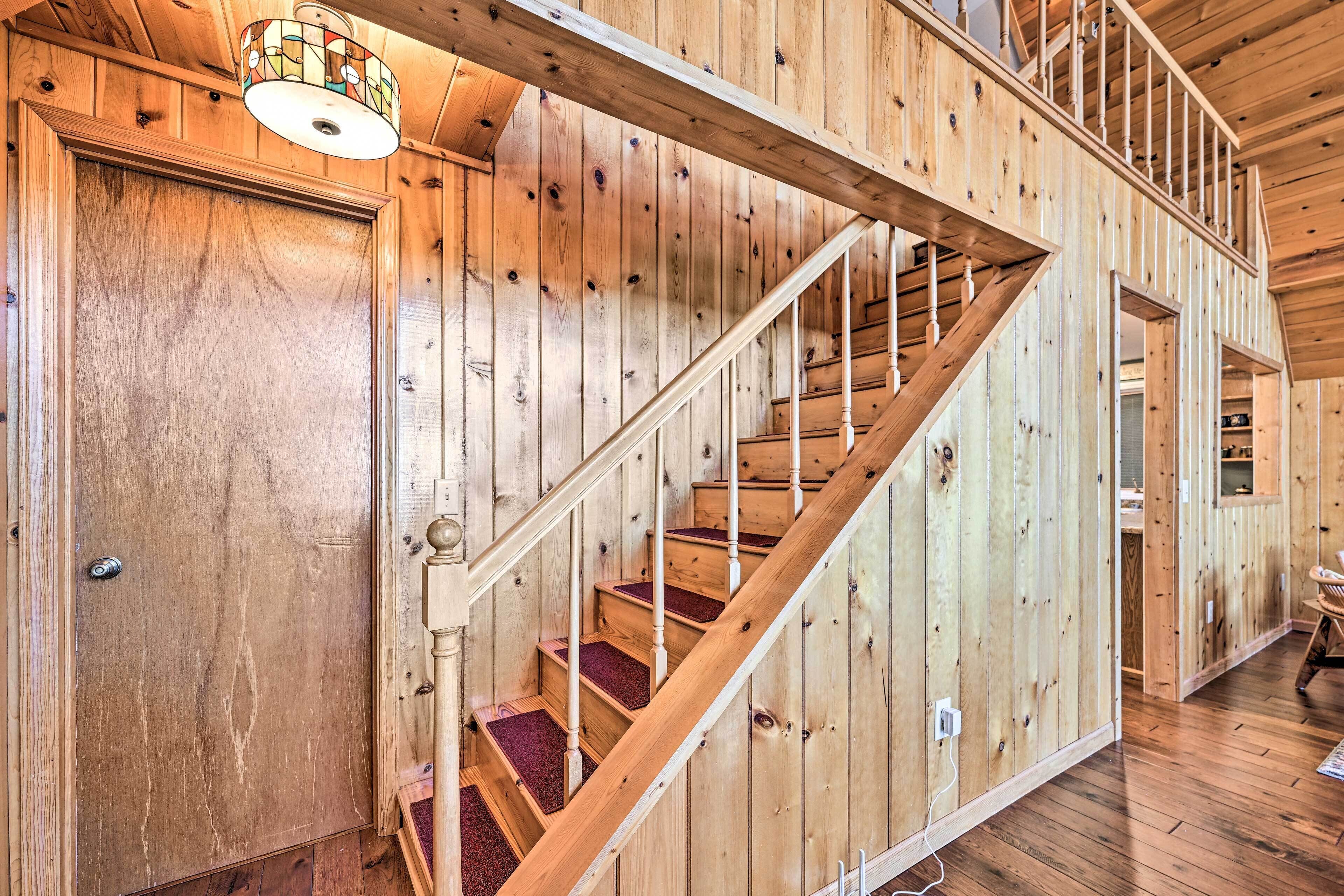 Una escalera de madera con peldaños alfombrados de rojo y barandilla blanca.