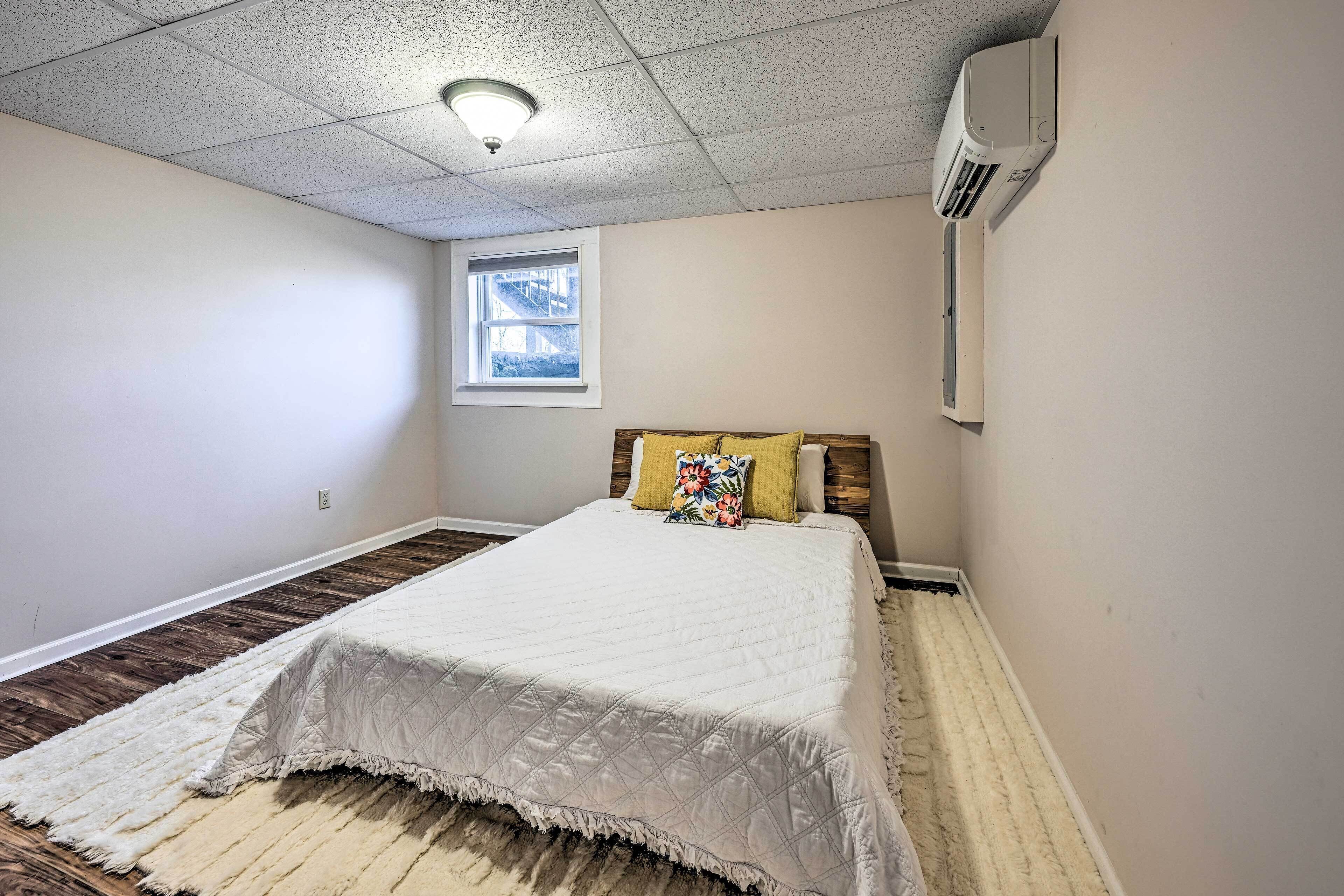 A bedroom with a bed, a window, and an air conditioning unit.