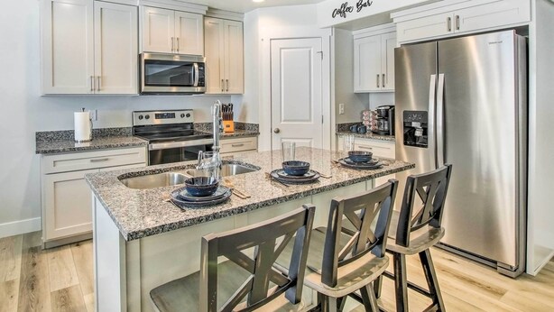 A modern kitchen with white cabinets, a stainless steel refrigerator, a built-in oven, and a granite countertop. - Garden City Vacation Rental - 1 Mi to Beach! (Garden City)