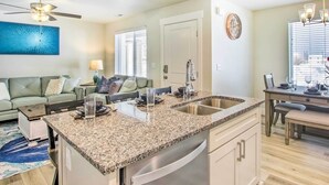 A modern kitchen with granite countertops, stainless steel appliances, and a dining area with a wooden table and chairs. - Garden City Vacation Rental - 1 Mi to Beach! (Garden City)