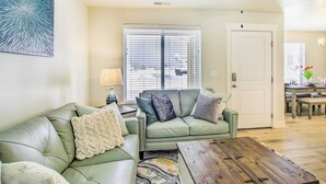 A living room with a green sofa, a wooden coffee table, and a patterned rug. - Garden City Vacation Rental - 1 Mi to Beach! (Garden City)
