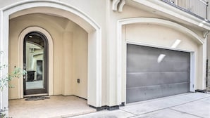 Une entrée d’immeuble avec une porte de garage, un petit porche et un balcon doté d’une balustrade.