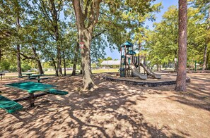 Ein Park mit Picknicktischen, einem Spielplatz und einem überdachten Bereich.