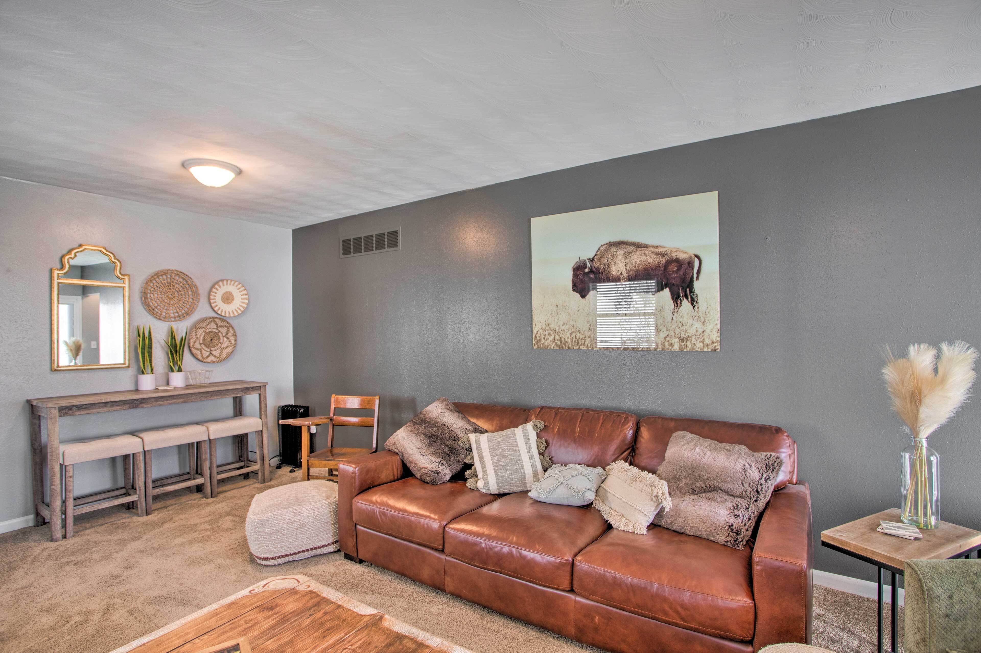 A living room with a brown leather sofa, a wooden bench, and a small table with a vase.
