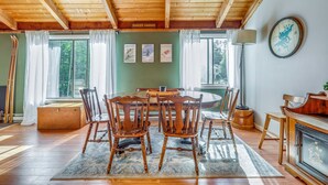 Un comedor de madera con una mesa, sillas, una lámpara y cuadros en la pared.