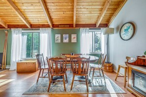 A wooden dining area with a table and chairs, a lamp, and framed pictures on the wall. - Unique Thornton Townhome: Swim, Ski, & Hike! (Thornton)