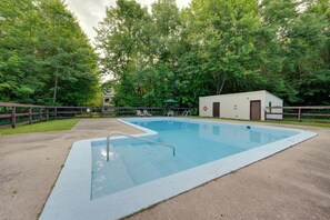 A rectangular swimming pool with a diving board, surrounded by a wooden fence and trees. - Unique Thornton Townhome: Swim, Ski, & Hike! (Thornton)
