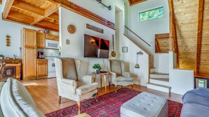 Amplia sala de estar con techo alto, vigas de madera, cocina equipada con electrodomésticos modernos y un rincón de descanso acogedor.