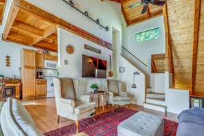 A spacious living area with a high ceiling, wooden beams, a kitchen with modern appliances, and a cozy seating arrangement. - Unique Thornton Townhome: Swim, Ski, & Hike! (Thornton)