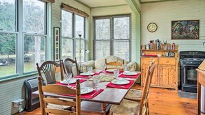 A dining room with a wooden table set for four, surrounded by wicker chairs. - Vintage Louisiana Vacation Rental Home (New Roads)