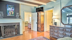 A room with a fireplace, wooden dresser, and a large mirror. - Vintage Louisiana Vacation Rental Home (New Roads)