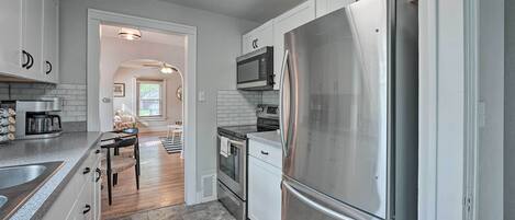A modern kitchen with white cabinets, stainless steel appliances, and a central island.