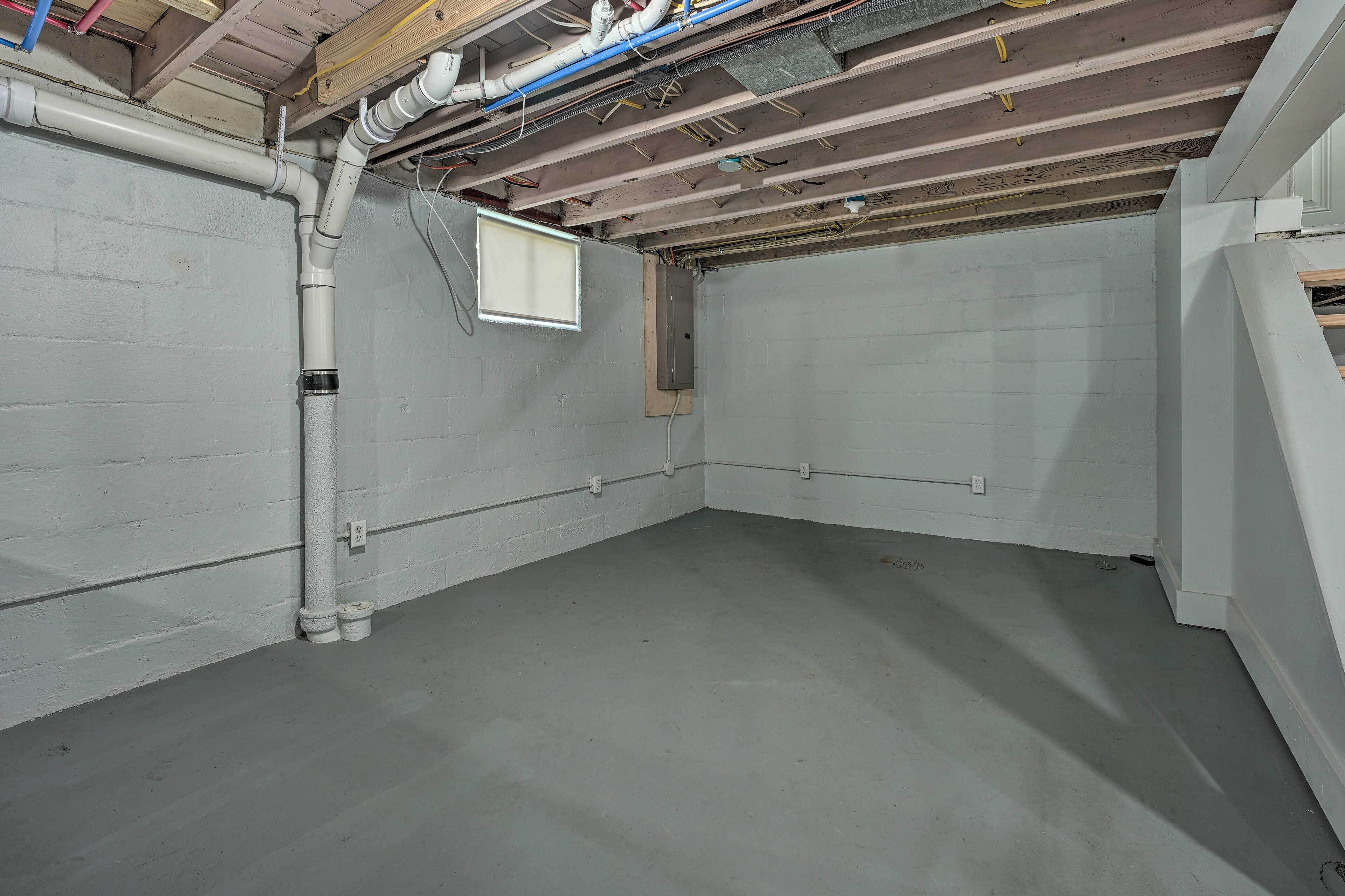 A basement with exposed wooden beams, white walls, and a concrete floor.