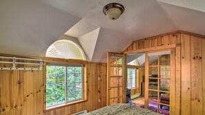 Ein Zimmer mit Holzboden, einem Bett, einem Fenster und einer Tür zu einem anderen Raum.