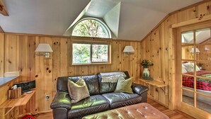 Ein gemütliches Zimmer mit Ledersofa, kleinem Schreibtisch und einem Bett mit rotem und schwarzem Karomuster.