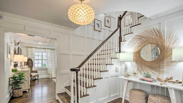 A staircase with white railings and wooden steps, leading to a landing with a round mirror and decorative items. - Stunning Charlotte Home: Private Pool! (Charlotte)