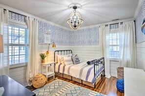 A bedroom with a bed, a bedside table, a lamp, and a wall with a geometric pattern. - Stunning Charlotte Home: Private Pool! (Charlotte)