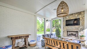A cozy living room with a stone fireplace, a wooden bench, and a wicker pendant light. - Stunning Charlotte Home: Private Pool! (Charlotte)