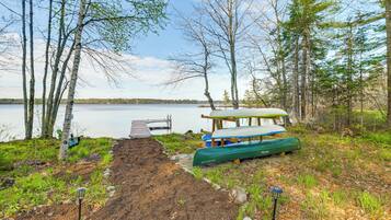 A lakeside campsite with a dock, a covered picnic table, and a canoe.