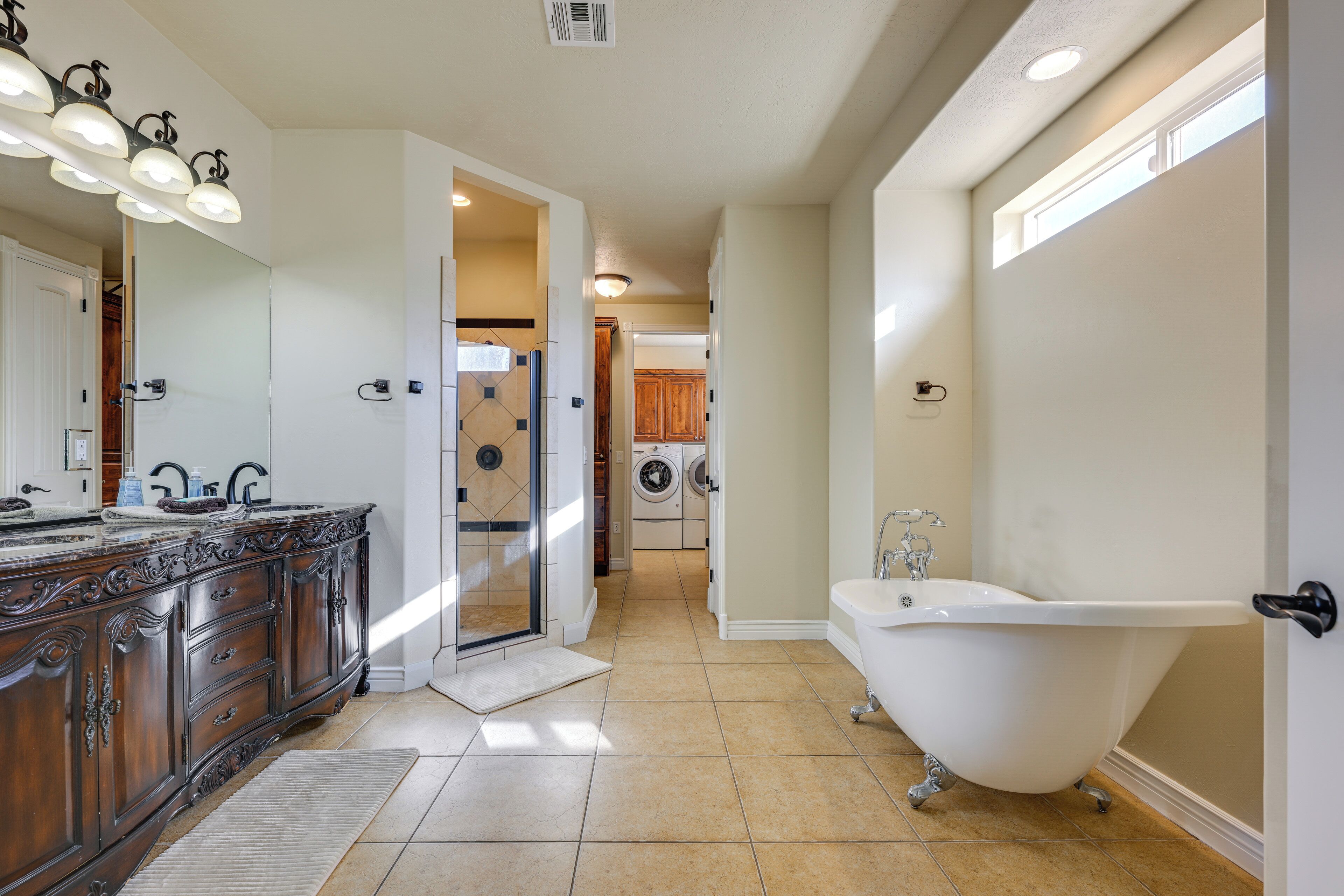 Een ruime badkamer met een vrijstaand bad, een groot wastafelmeubel met spiegel en een inloopdouche.