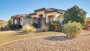 A residential house with a tiled roof, a landscaped front yard with gravel and shrubs, and a clear blue sky. - Utah Retreat w/ Heated Pool, Grill & Fire Pit! (Hurricane)
