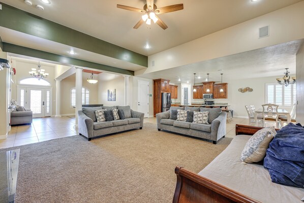 Relax in this spacious living area with a high ceiling, open kitchen, and dining space, featuring a sofa, chairs, and a bed.
