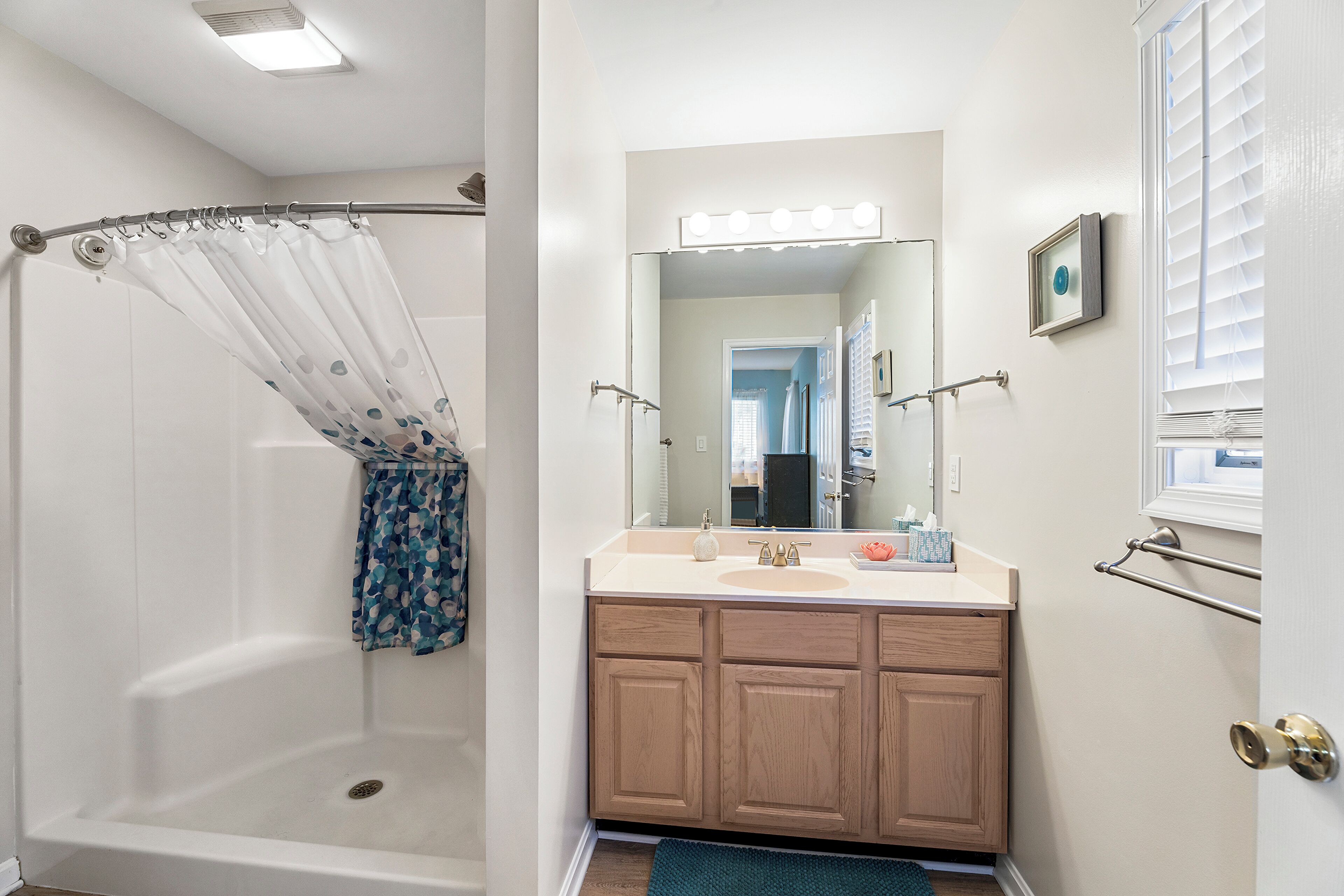 A bathroom with a shower, vanity, and a large mirror.