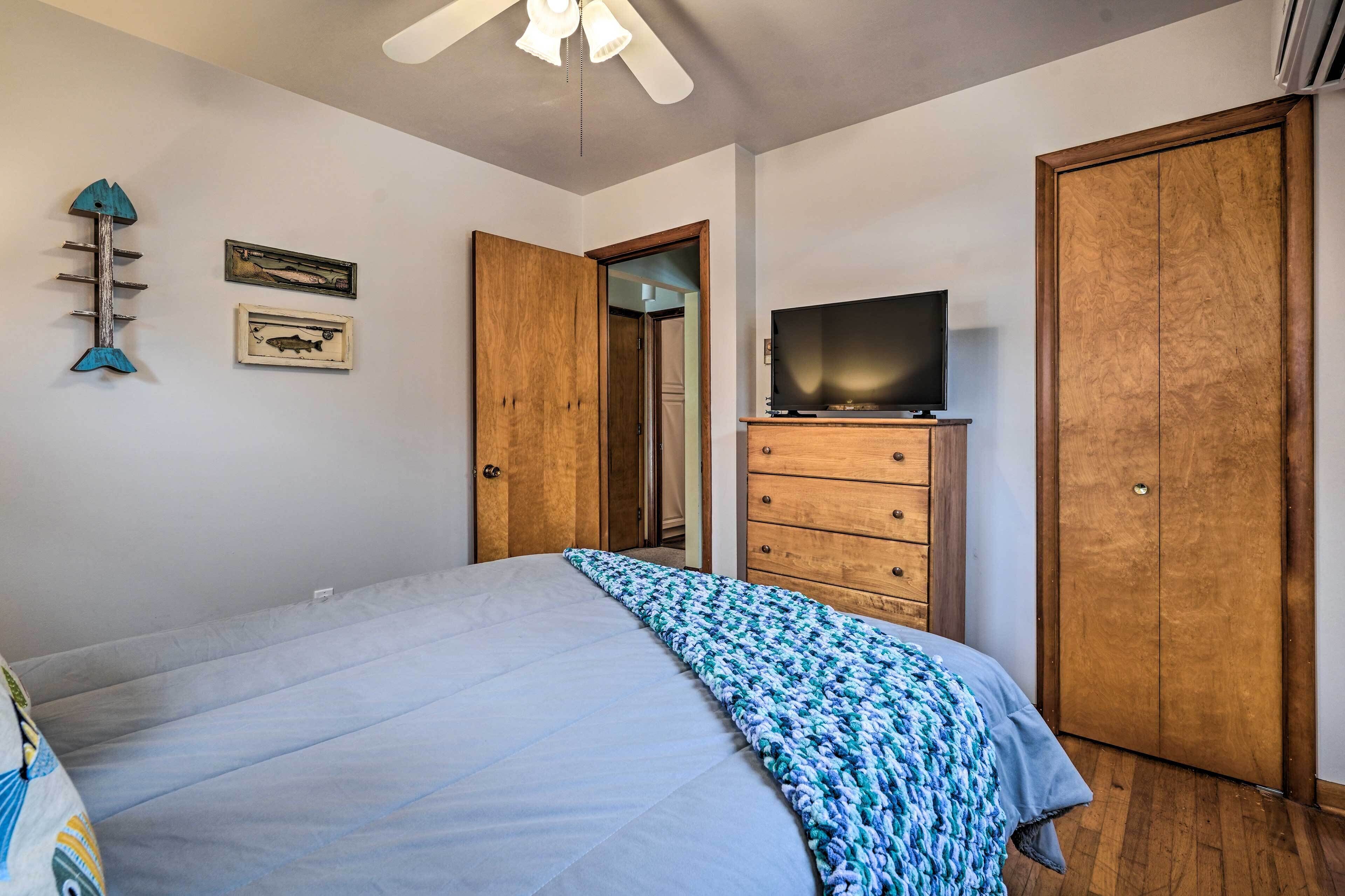 A bedroom with a bed, a dresser, a television, and wooden wardrobes.