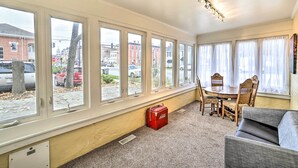 A room with large windows, a dining table with chairs, a red cooler, and a grey sofa. - Historic Troy Home Enjoyable Dining Steps Away (Troy)