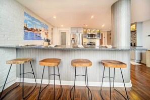 A kitchen with a central island, bar stools, stainless steel appliances, and a mural on the wall. - Waterfront Cleveland Apt ~ 1 Mi to Downtown (Cleveland)