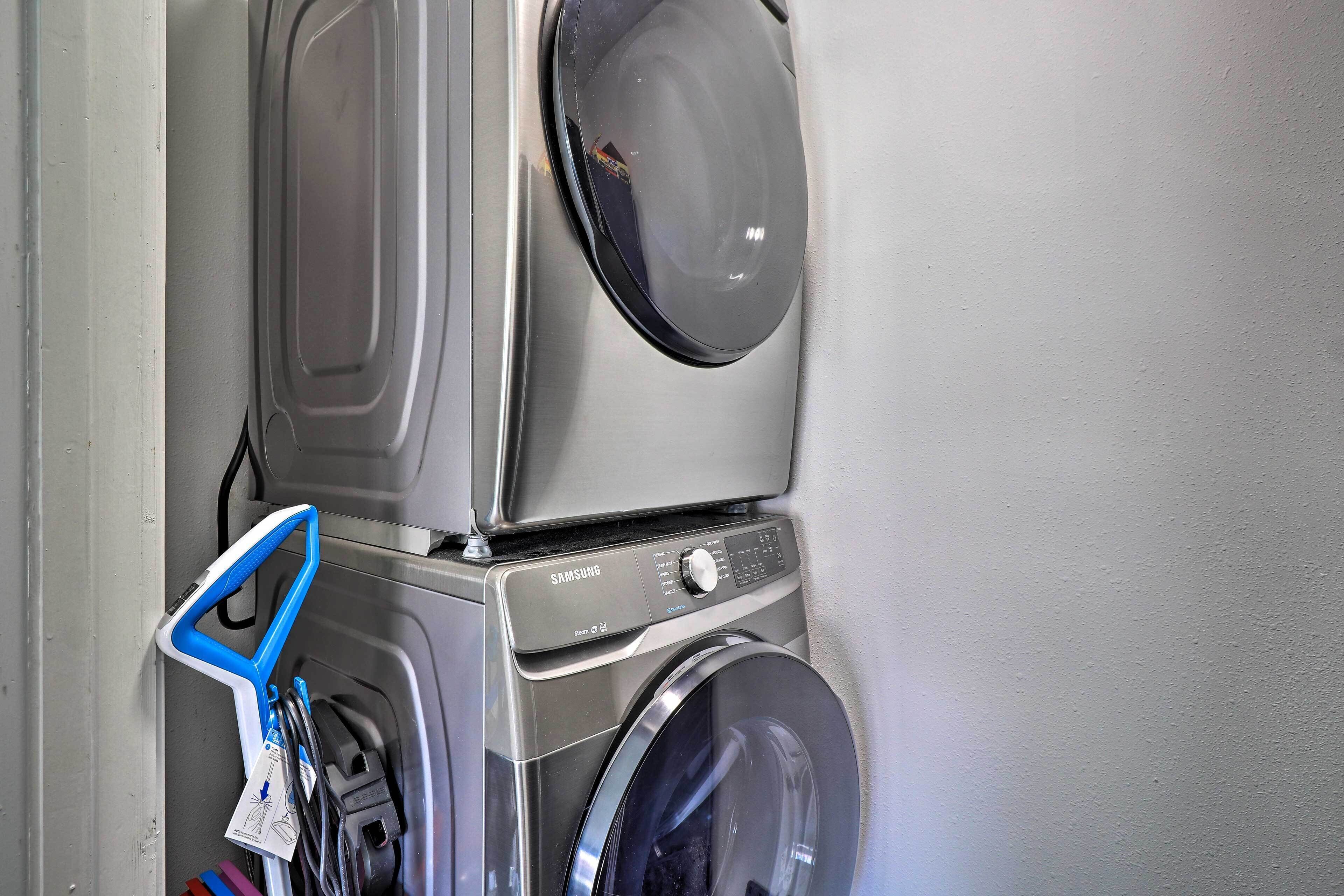 A stacked washer and dryer unit with a control panel and a blue hanger.