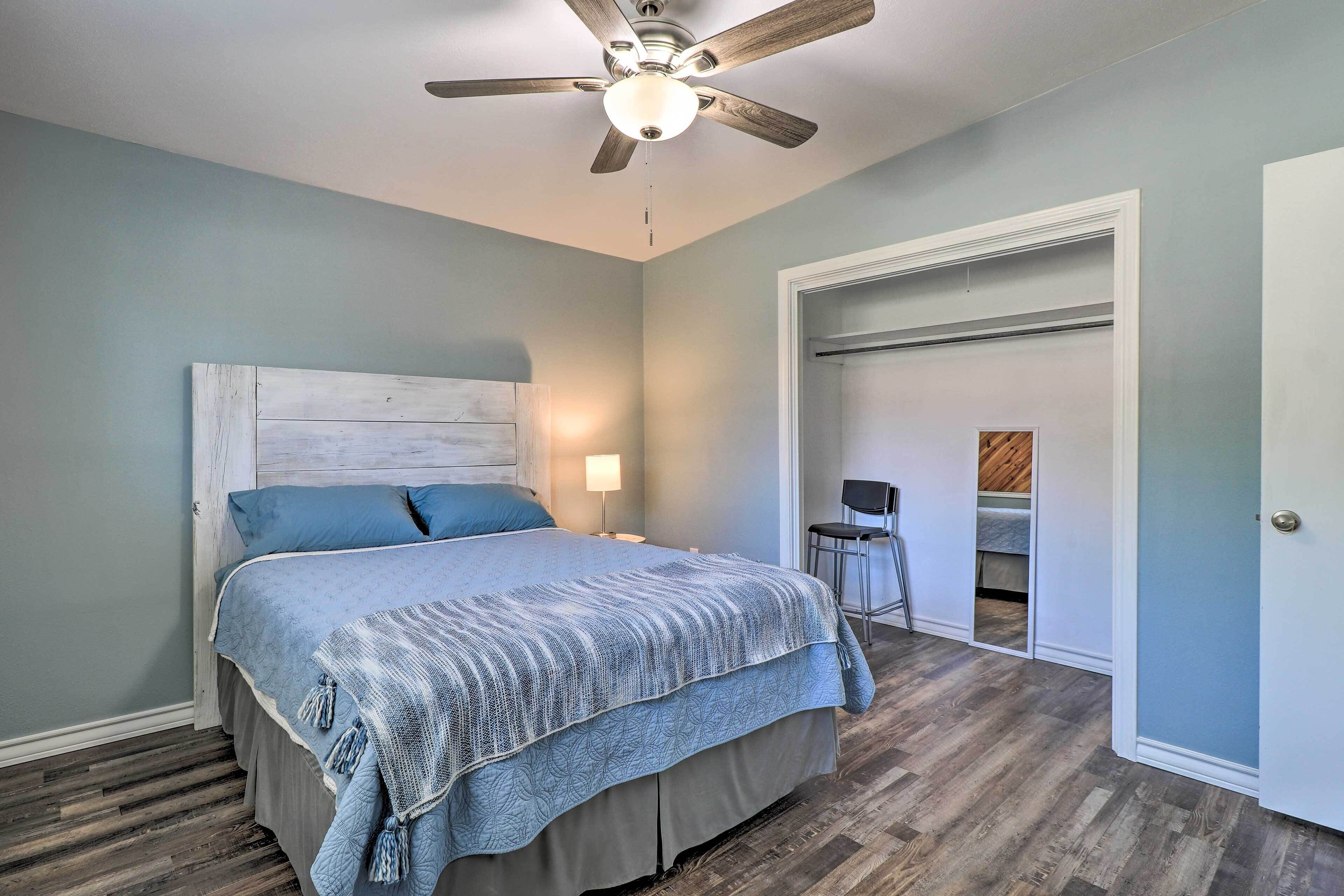 A bedroom with a bed, a ceiling fan, a nightstand, and a chair.