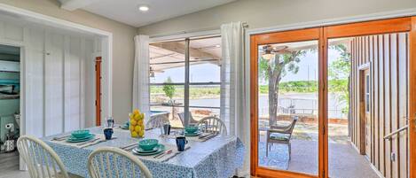 A dining area with a table set for four, a sliding glass door leading to an outdoor patio, and a view of the outdoors.