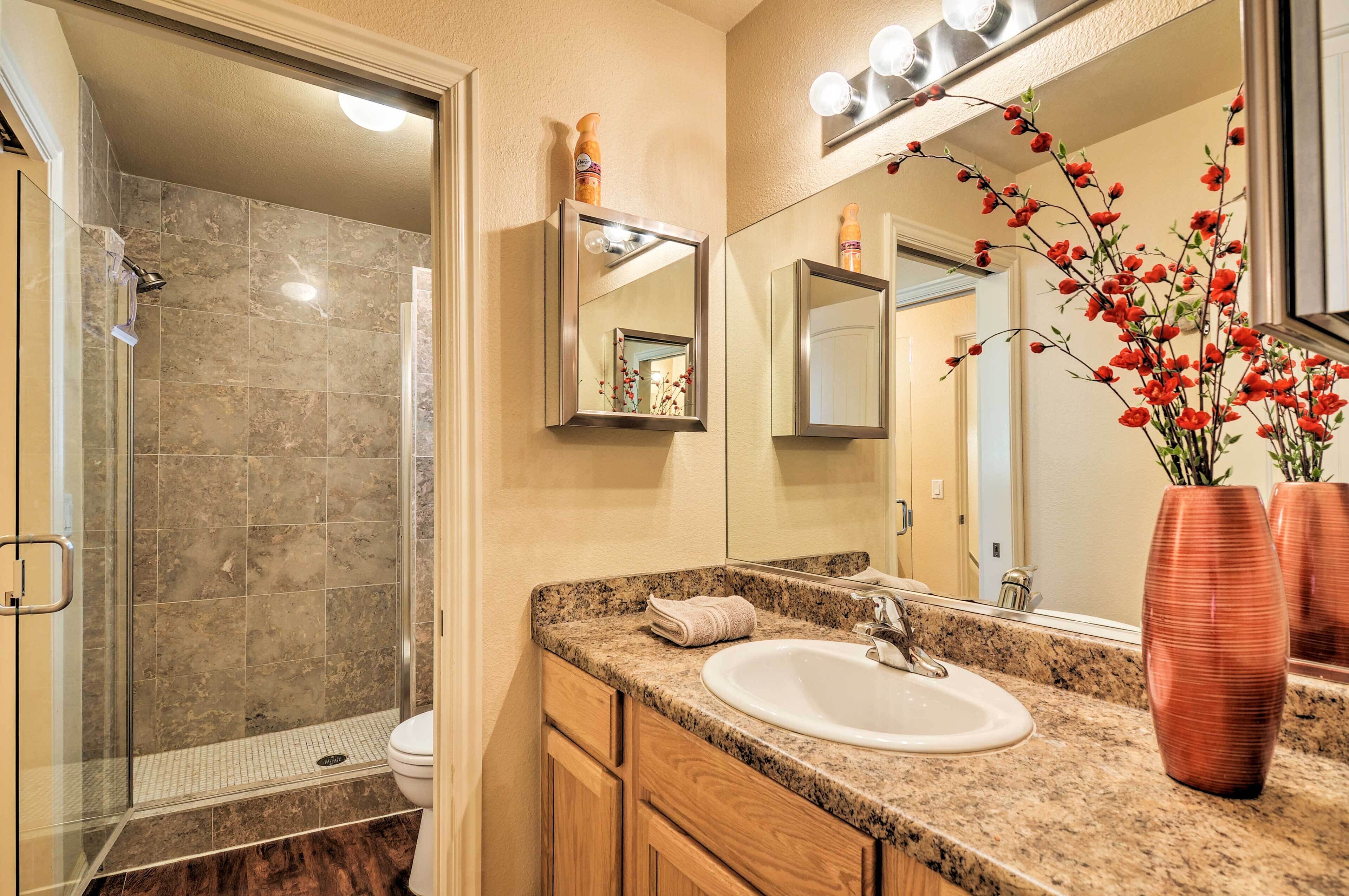 A bathroom with a glass shower enclosure, a sink, and a mirror.