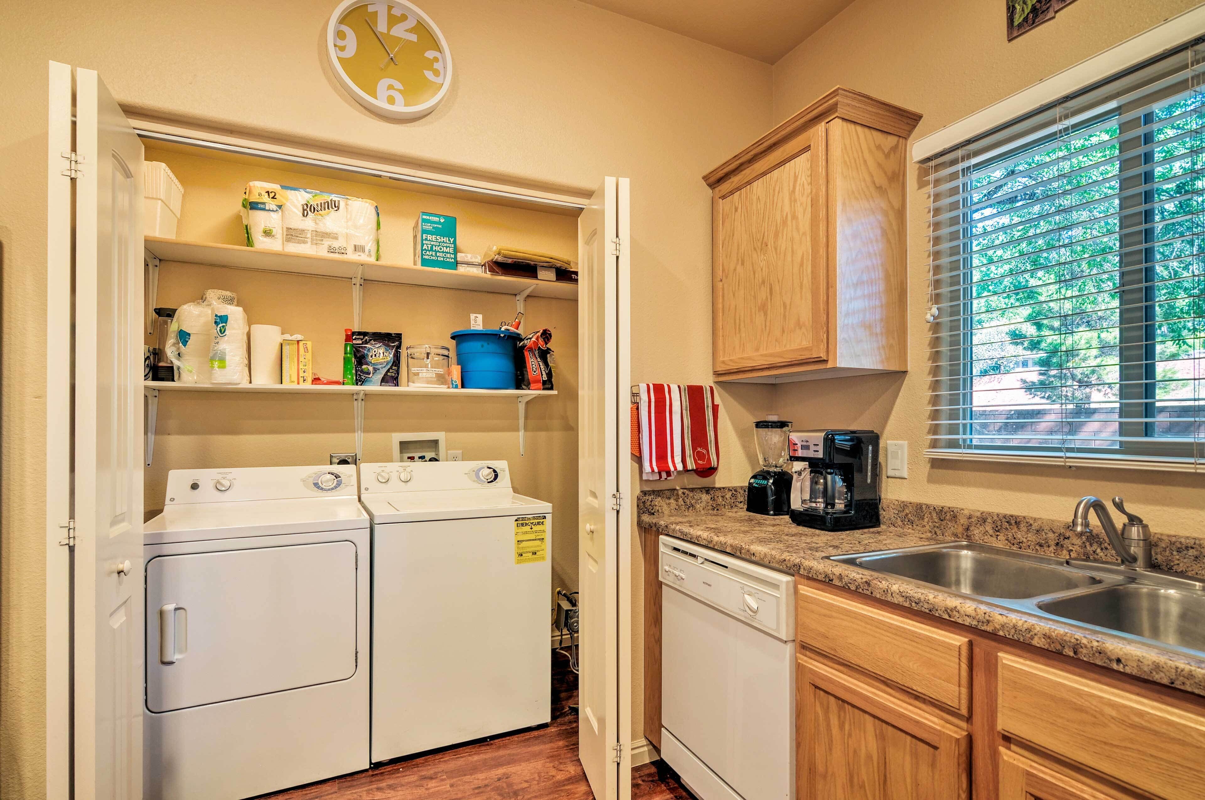 A compact kitchen with a built-in washer and dryer, a sink, and a window with blinds.