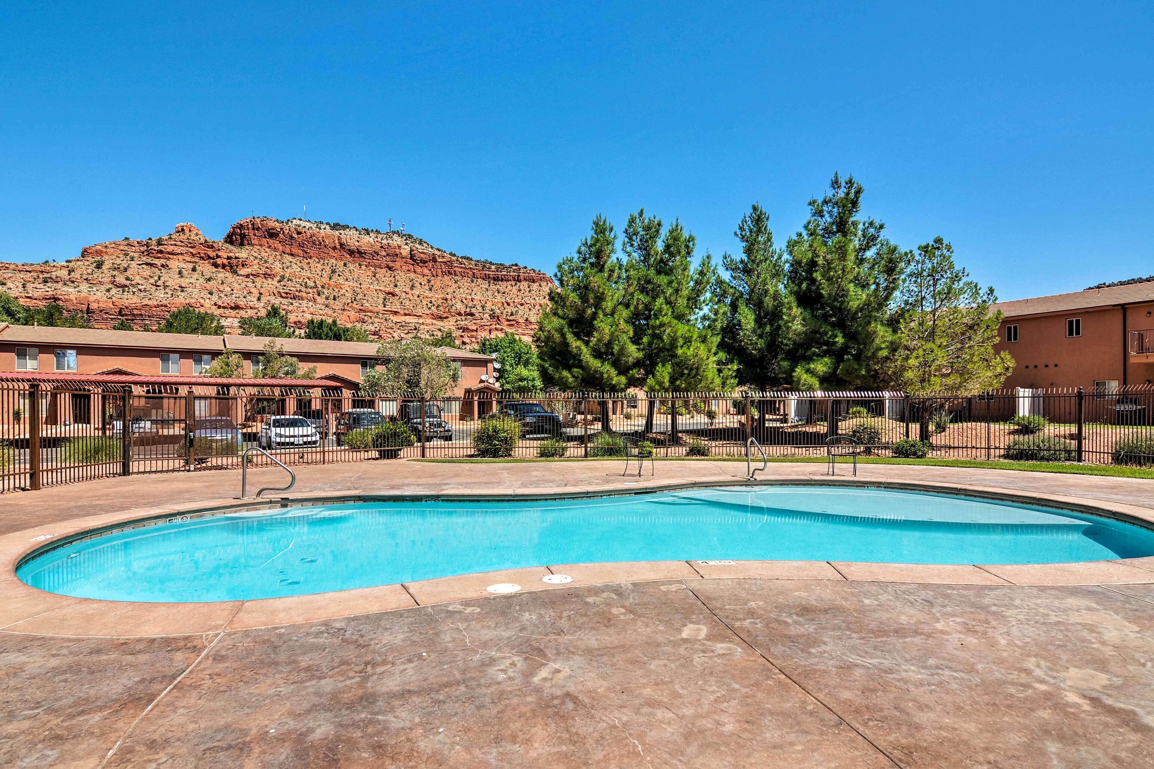 A swimming pool with a clear view of a red rock formation in the background.