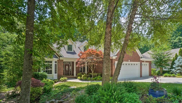 A two-story house with a brick facade, a front garage, and a well-maintained garden with various plants and a stone pathway. - Tellico Village Getaway w/ Theater, Game Room (Loudon)
