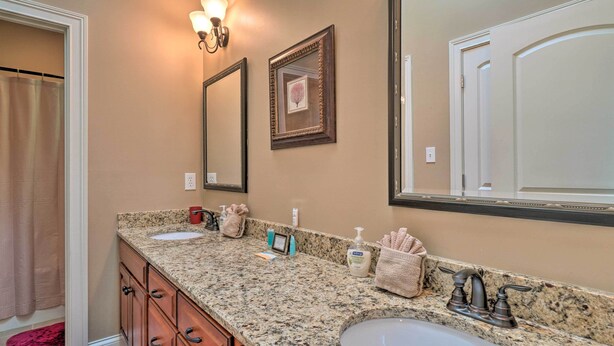 A bathroom with a granite countertop, two sinks, a large mirror, and a towel rack. - Tellico Village Getaway w/ Theater, Game Room (Loudon)