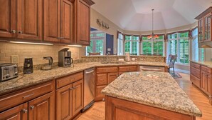 A spacious kitchen with granite countertops, wooden cabinets, and a large island. - Tellico Village Getaway w/ Theater, Game Room (Loudon)